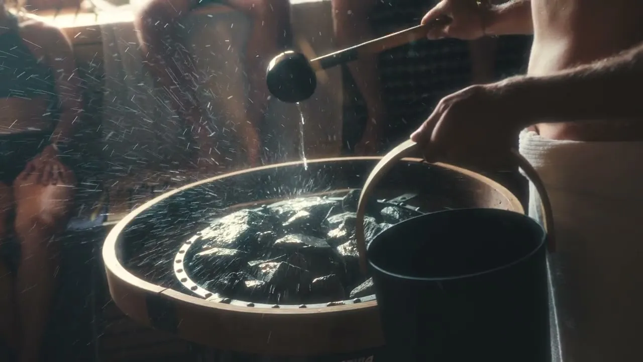 Saunameister pouring löyly over the kiuas stones at Blue Mountains Sauna