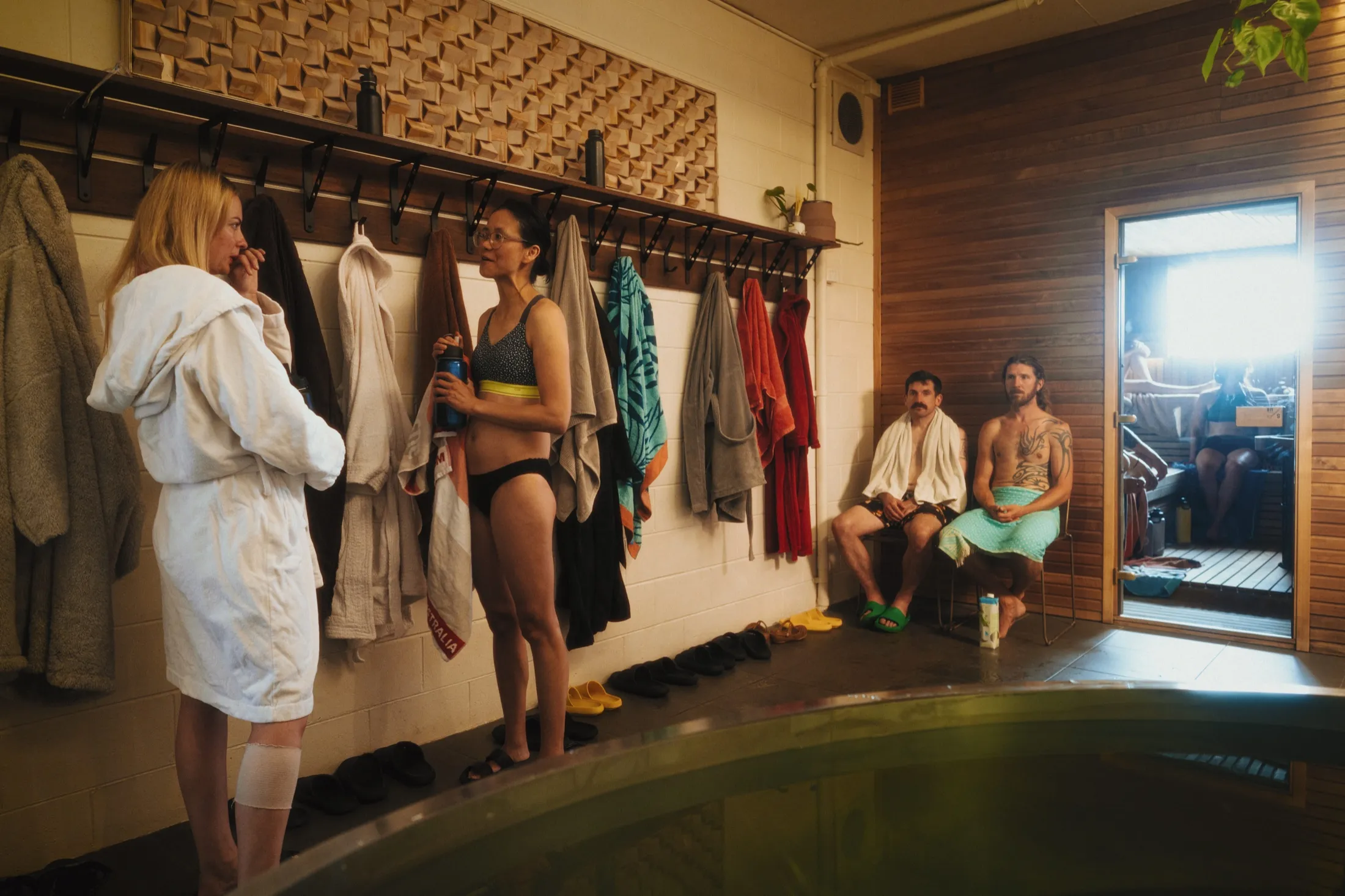 Robes and towels on the wet-area hook rail beside the plunge and sauna