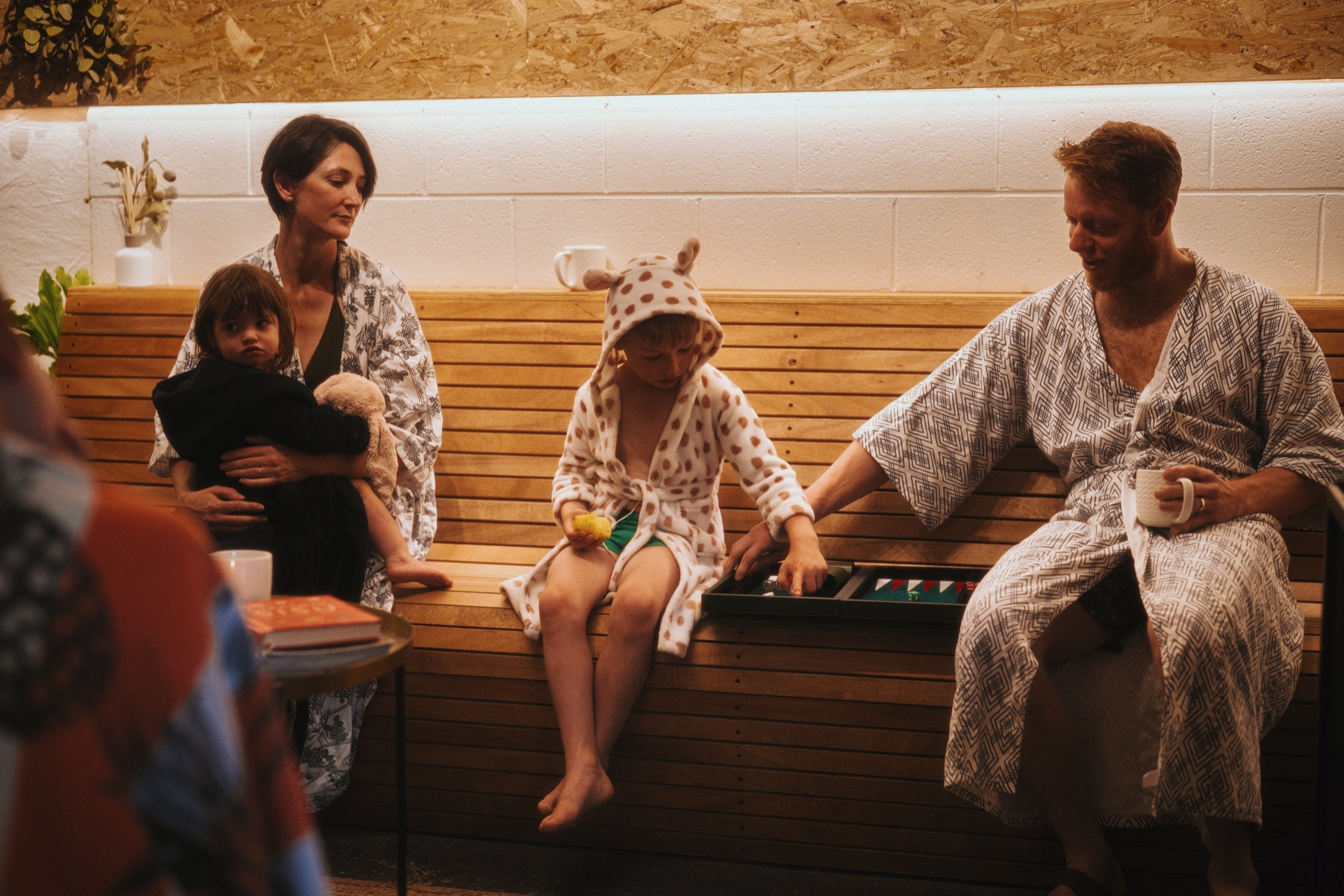 Family relaxing in robes on benches
