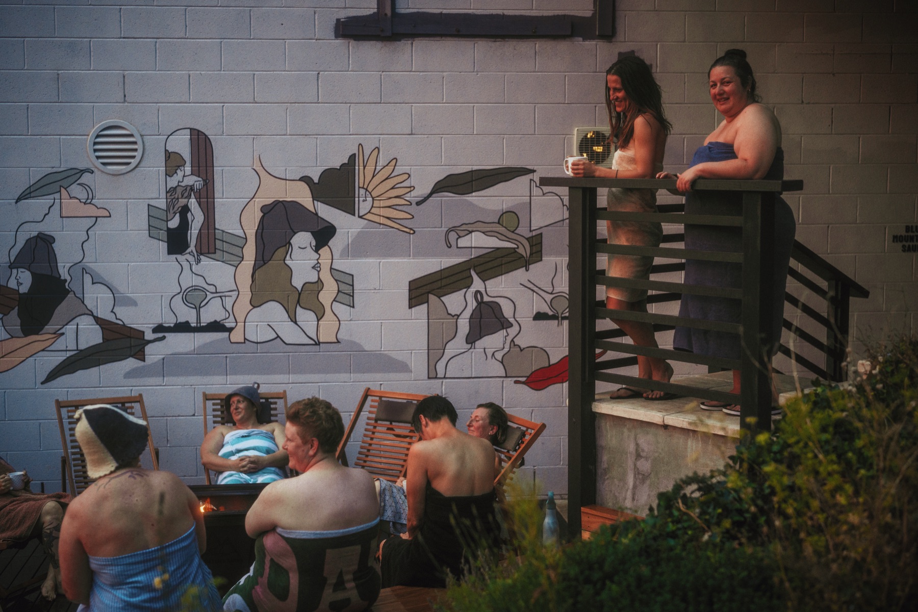 Bathers relaxing by the mural at dusk